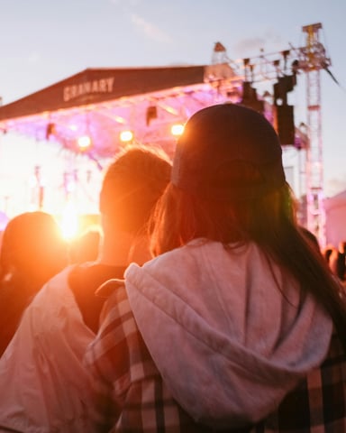 Outdoor music festival at golden sunset with warm stage lights and crowd