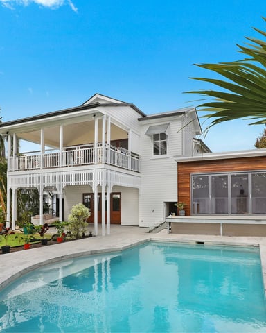 Bright white two-storey family home with pool and palm trees