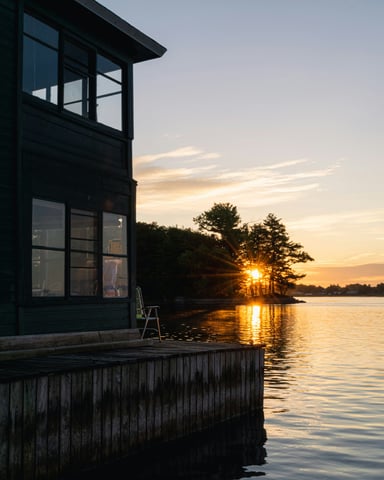 Dark lake house on a wooden dock at golden sunset with trees silhouetted on the water