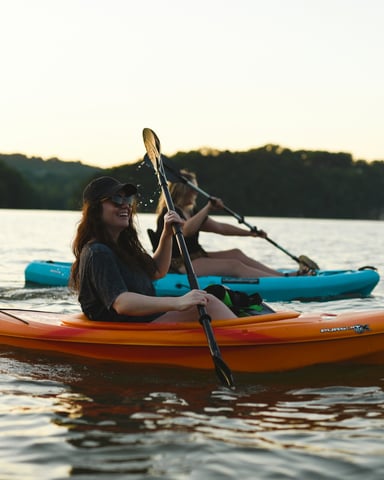 Woman kayaking at golden hour on a wooded lake