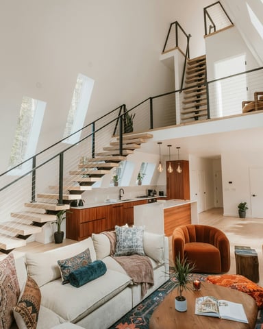 Bright A-frame vacation rental interior with soaring ceilings, warm terracotta chairs, and open kitchen