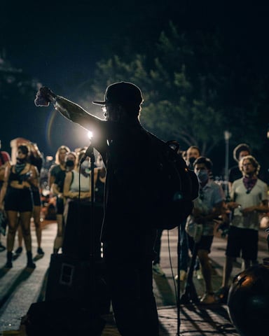 Street musician silhouetted against a crowd at night in Austin