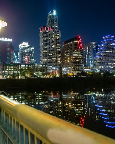 Austin skyline at night reflected in Lady Bird Lake from the 1st Street bridge