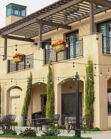 Winery building with outdoor seating, wine barrels, string lights, and a pergola
