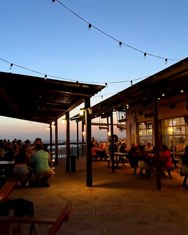 Oasis outdoor terrace at dusk with string lights over Lake Travis, Austin