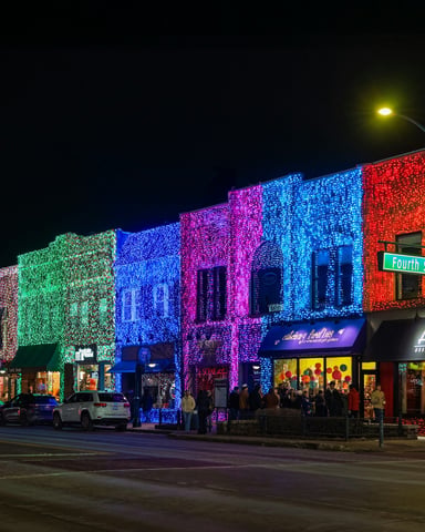 Downtown street lit up in vivid multicolored holiday lights at night