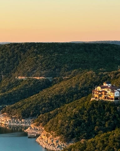 Aerial view of Lake Travis winding through green Hill Country hills at sunset