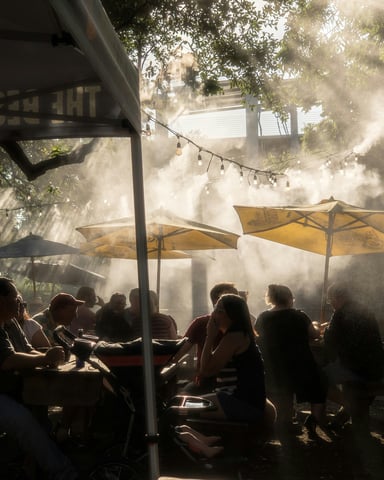 Outdoor bar terrace with mist sprayers and string lights under oak trees