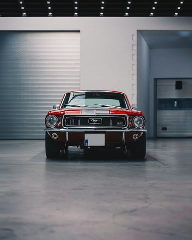Red classic Mustang parked in a clean modern garage with polished concrete floors and white roller door