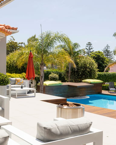 Luxurious backyard patio with pool, palm trees, and sun loungers