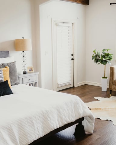 Well-appointed bedroom with dark wood floors, mustard accent pillows, and cowhide rug