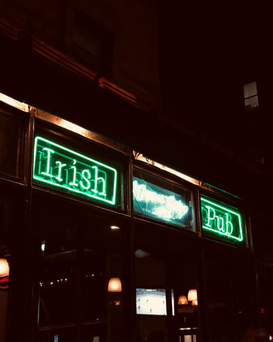 Green neon Irish Pub sign glowing against a dark facade