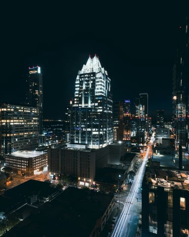 Austin downtown at night from above with light trails on Congress Avenue and the Frost Bank Tower glowing