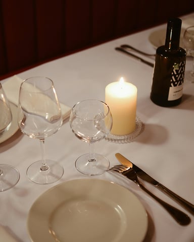 Elegant French bistro table set with white tablecloth, candle, and wine glasses