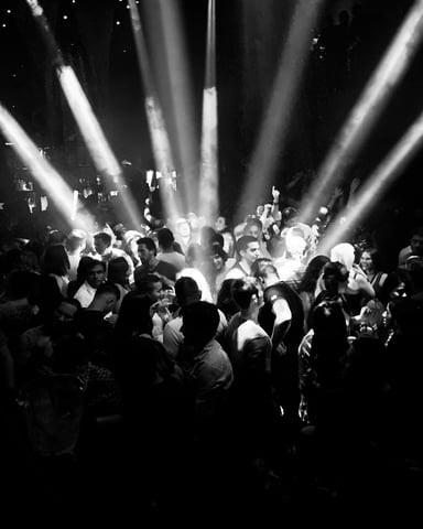 Concert crowd under dramatic stage beams in a packed music venue