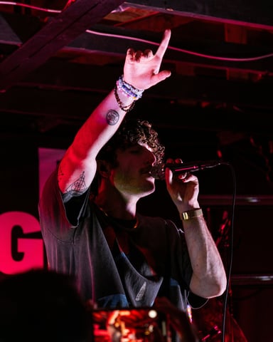Singer performing on stage under red lights at an intimate Austin music venue