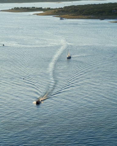Aerial view of two boats cutting wakes across Lake Travis at golden hour