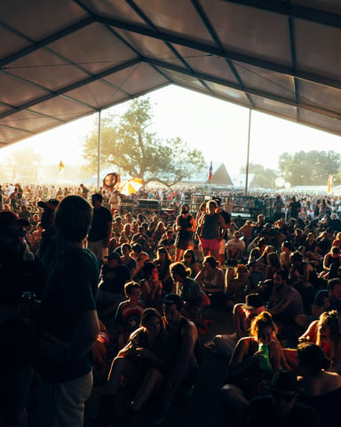 Packed ACL festival crowd under a tent at golden hour