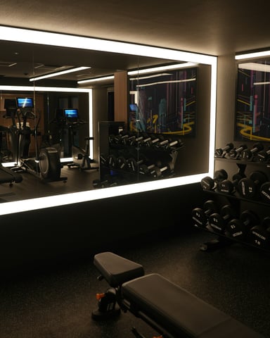 Sleek dark hotel gym with LED strip lighting, treadmills, and dumbbell rack reflected in mirror