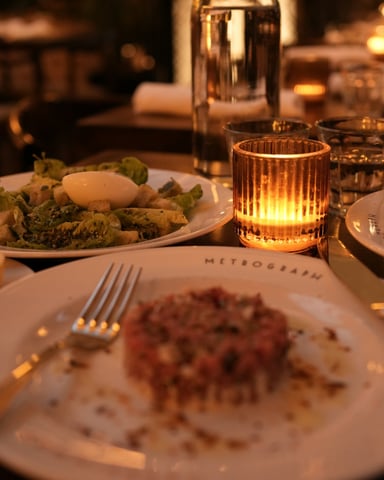 Candlelit dinner table with food and glowing amber candle at a restaurant