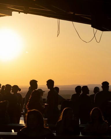 Silhouetted crowd at an outdoor Austin venue against a blazing orange sunset