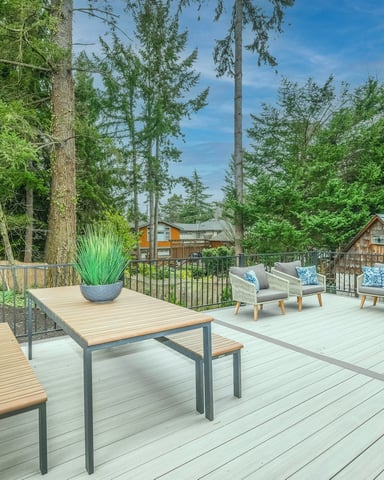 Spacious deck with outdoor dining table surrounded by tall trees