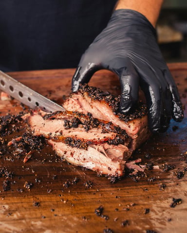 Pitmaster slicing through perfectly smoked brisket on a wooden cutting board