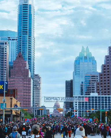 Massive crowd walking down Congress Avenue toward the Austin skyline and Capitol dome