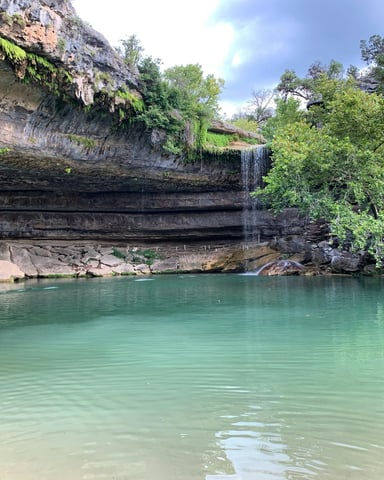 Hamilton Pool Preserve with turquoise water under a limestone overhang and waterfall