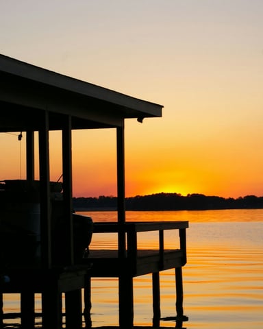 Dock silhouette at golden sunset over calm Texas lake water