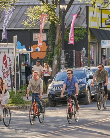 Cyclists along an East Austin street with colorful local storefronts
