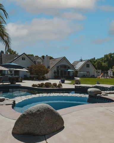 Large vacation home with pool, palm trees, and bright blue sky
