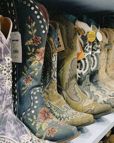 Ornate cowboy boots with floral patterns lined up on a store shelf