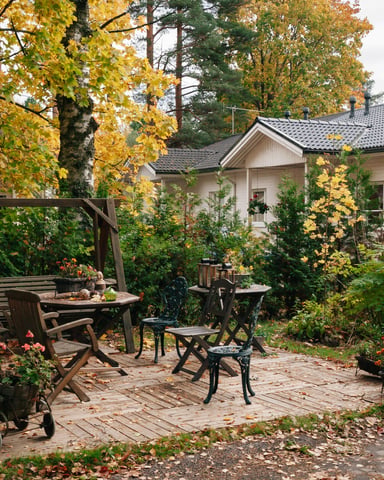 Outdoor patio with wooden furniture surrounded by golden autumn foliage