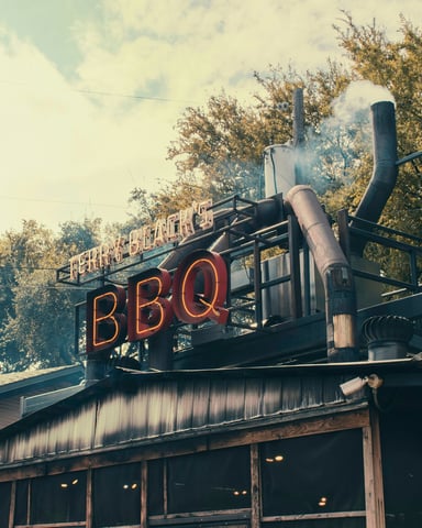 BBQ neon sign with smoke rising through trees at a Texas barbecue joint