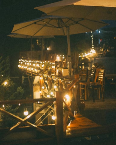 Outdoor restaurant deck at night with string lights and patio umbrellas