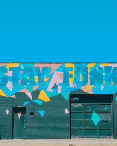 Stay Funky mural on a teal building under a vivid blue Austin sky