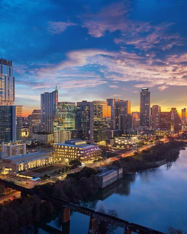 Austin skyline at sunrise with dramatic blue and orange sky reflecting on the Colorado River