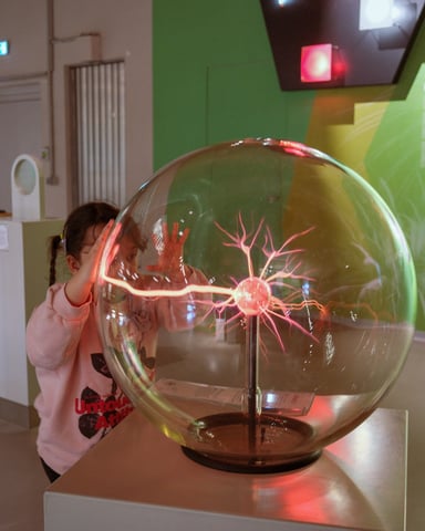 Child touching a plasma ball in a glowing green science exhibit