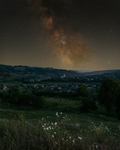 Milky Way arching over rolling green hills at night