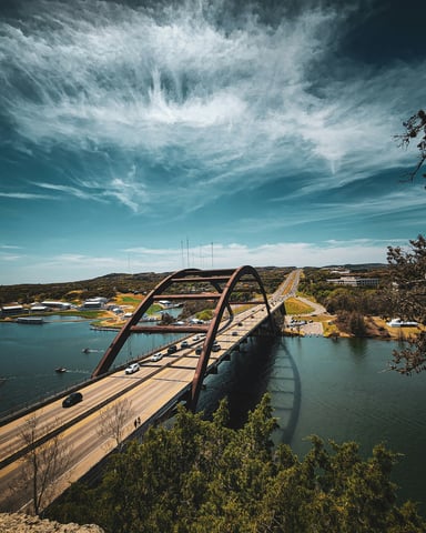 Aerial view of the 360 Bridge over Lake Austin with Hill Country in the background