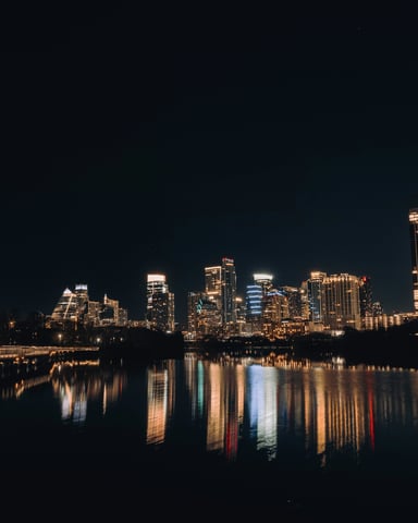 Austin skyline at night reflected in Lady Bird Lake with a pedestrian bridge in the foreground
