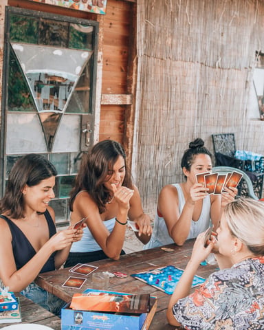 Group of women laughing and playing card games on a rustic outdoor patio
