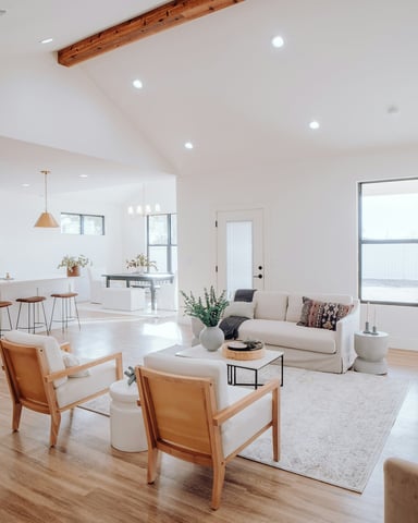 Bright open-plan living room and kitchen with vaulted ceiling, exposed beam, and warm wood floors
