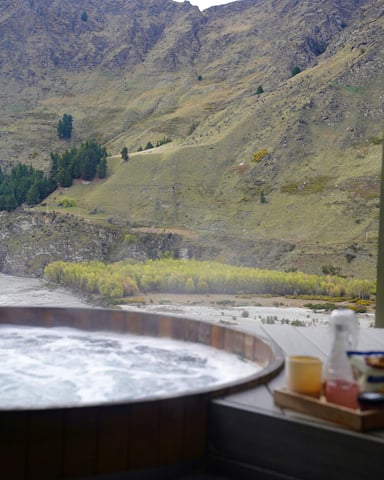Hot tub with drinks tray overlooking a wide mountain valley with autumn foliage