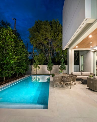 Modern home with glowing blue pool and outdoor seating at night