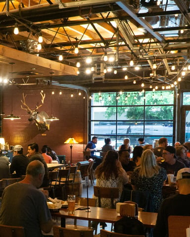 Lively East Austin brunch restaurant interior with exposed ceiling, string lights, and a full dining crowd