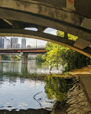 Runner under the Lamar bridge along Lady Bird Lake with the Austin skyline in the background