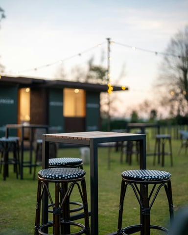 Outdoor bar patio with string lights at dusk, bungalow-style building in the background
