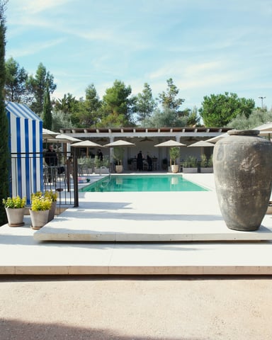Grand estate with a long pool, cypress trees, and stone urns